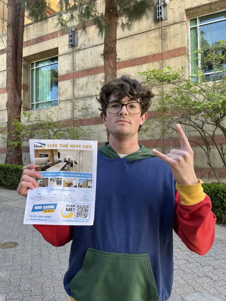 Student holding a flyer with information about The Hive Apartments - UCLA Student Apartments